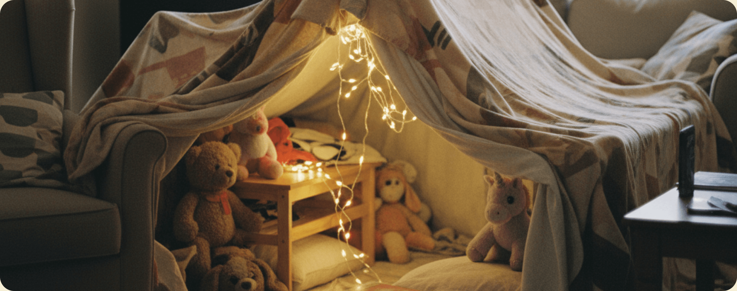 Children playing in a blanket fort with string lights